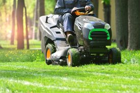 Professional lawn mower with worker cut the grass in a garden