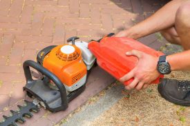 Man fills hedge trimmer with fuel Male gardener filling hedge trimmer with fuel
