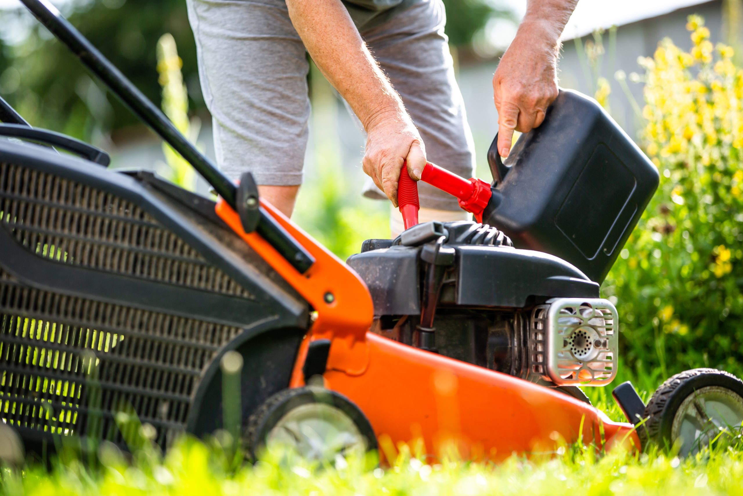 Man refueling lawnmower on his huge garden, gardening concept