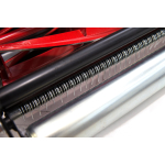 A close-up of a red cylinder lawn mower's spiral cutting blades and chrome roller.