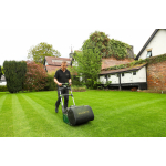 A man pushes a green Allett cylinder mower across a striped lawn in front of a period house.