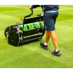 A man pushes a professional cylinder mower with grass collection boxes across a striped fine turf lawn.