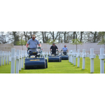 Three men wearing ear defenders push navy blue Allett walk-behind cylinder mowers between rows of white cross memorials.