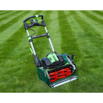 A green cylinder lawn mower with a battery pack sits on a striped lawn.
