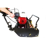 A close-up shows a person's hands adjusting the red petrol engine mounted on a black cylinder lawn mower.