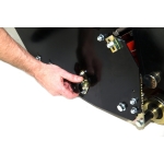 A hand turns an adjustment knob on the side panel of a black cylinder mower, with its chain drive visible.