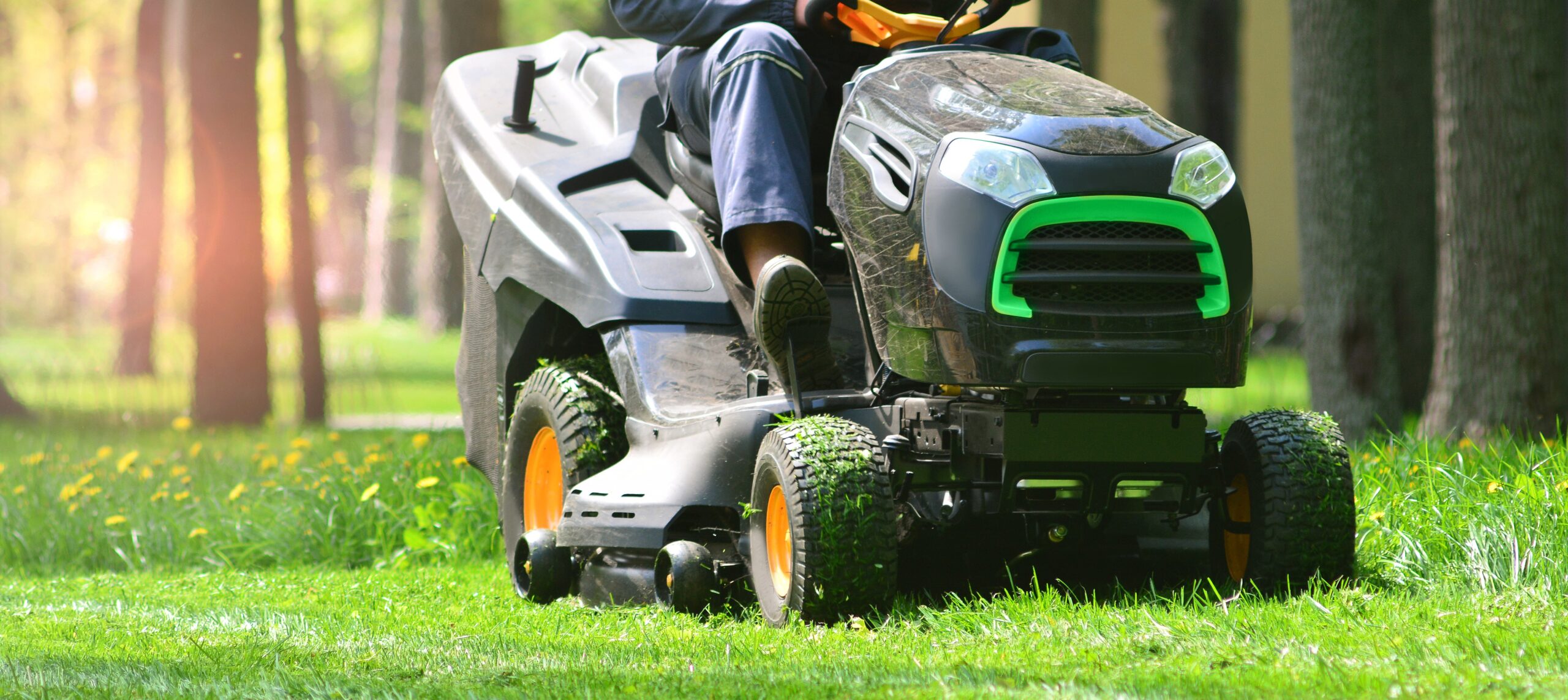 Professional lawn mower with worker cut the grass in a garden